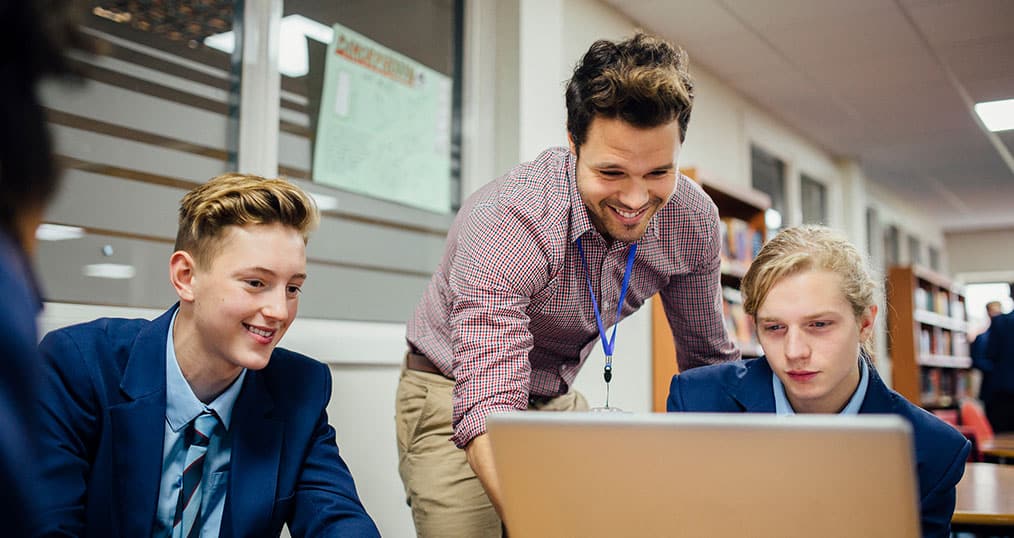 GCSE Teacher showing students content on laptop
